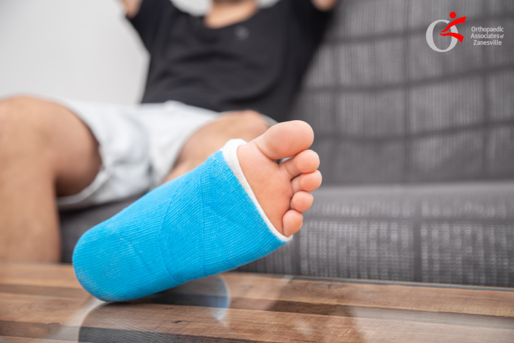 A man that was exercising is sitting on the ground holding his ankle in pain after fracturing his Talus in Zanesville, Ohio.